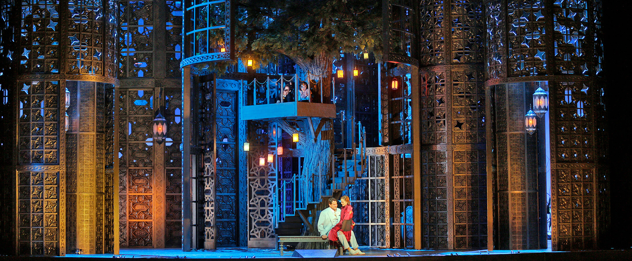 A stage scene with a woman sitting on a man as they are preparing to engage with the audience during a presentation or performance.