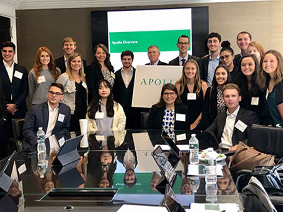 A diverse group of professionals smiling together in front of a conference table, capturing a moment of collaboration.