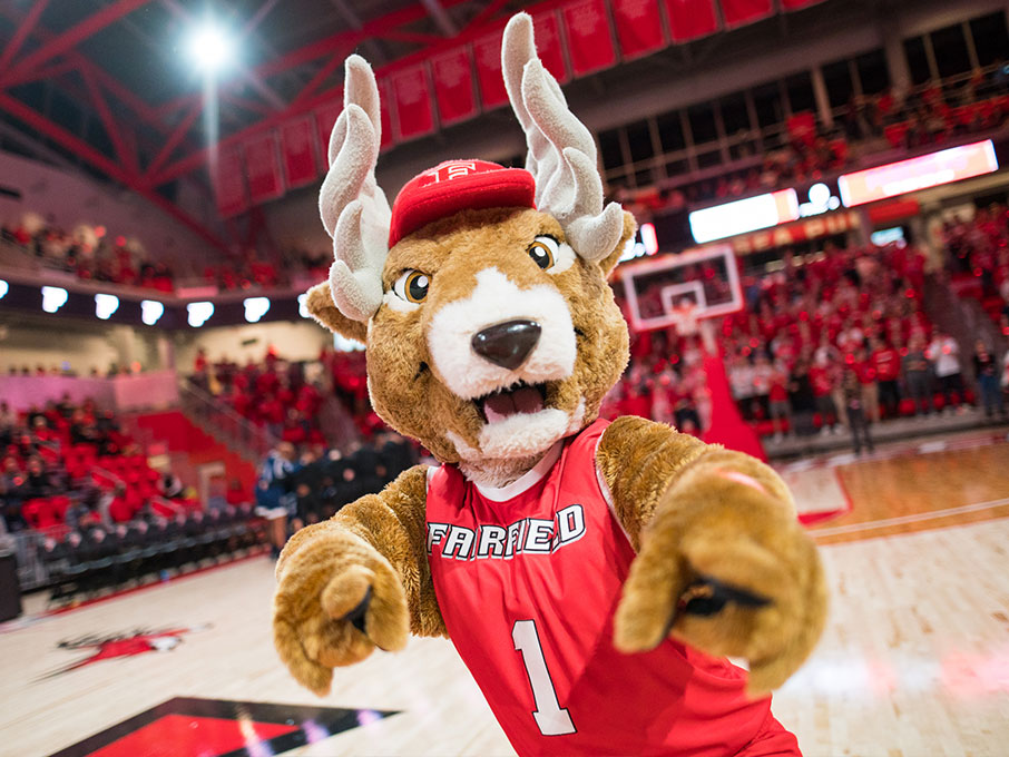 Lucas the mascot points to the camera in the arena.