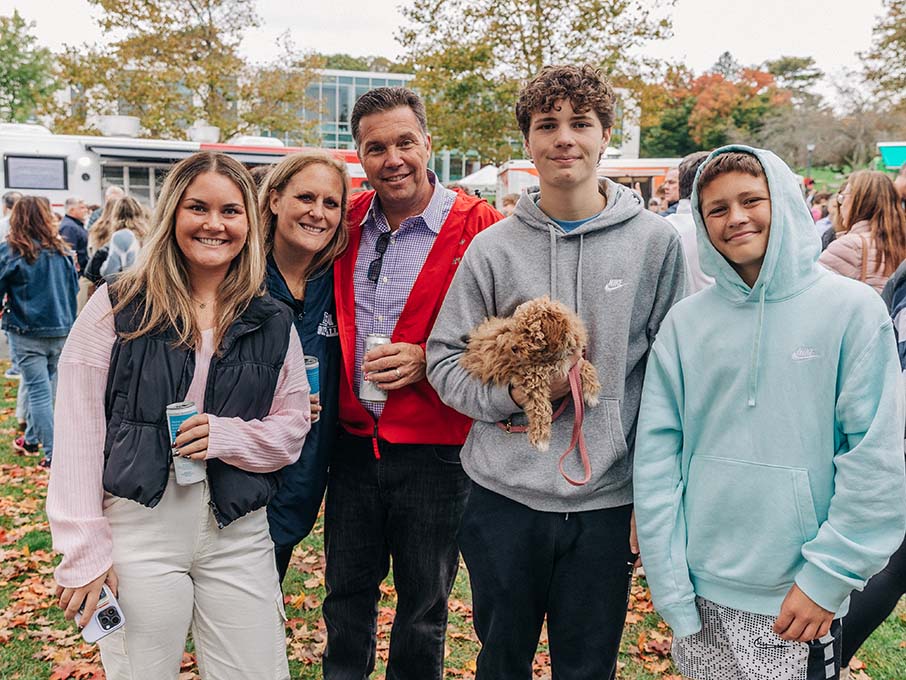 A family of three children and two parents pose for a photo with one child holding a dog.