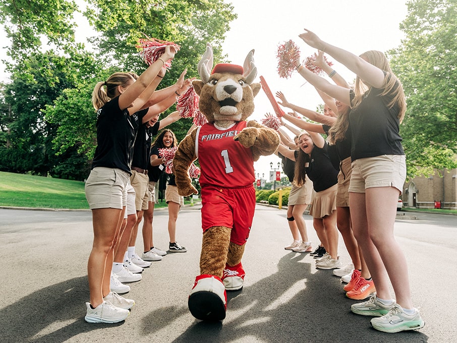 Orientation student leaders forming an archway for Fairfield's Lucas the Stag mascot to walk through.