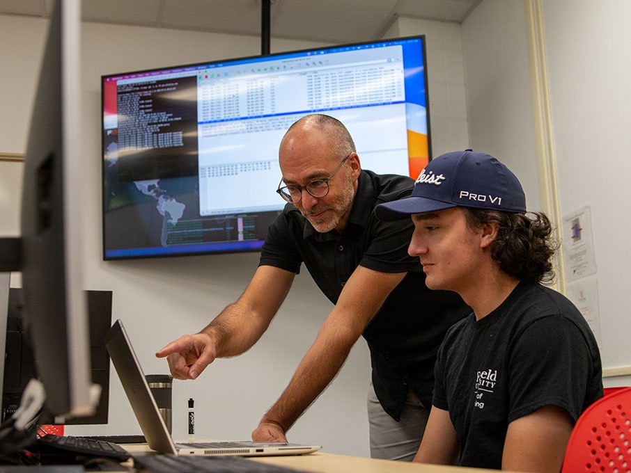 Cybersecurity professor going over the parameters of an assignment with a student in the cybersecurity lab.
