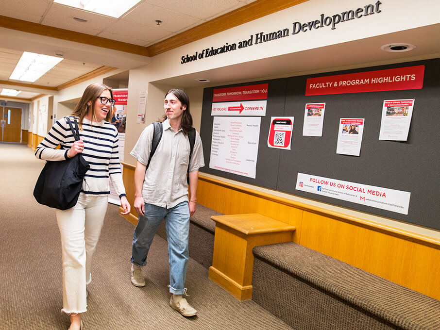 A pair of students strolling through a spacious hallway, surrounded by light and simple decor.