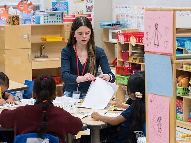 A certified teacher in Fairfield's master's program instructing a small group of students on an arts and crafts project.