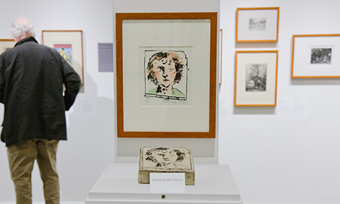A man observes an array of colorful artworks displayed in an Walsh Art Gallery.  