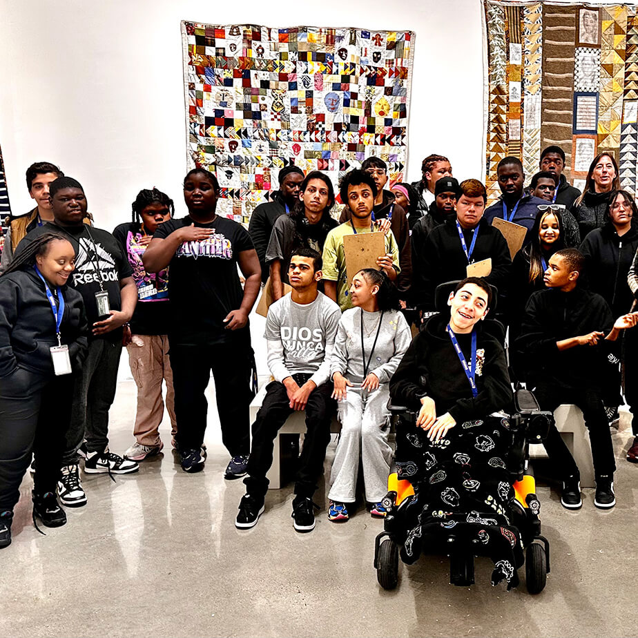 Several individuals stand together for a photo, with a large, colorful mural serving as the backdrop to their joyful gathering.