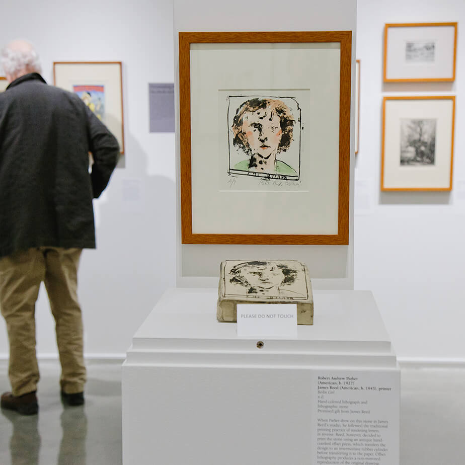 A man stands in front of a displayed drawing, intently examining its features and artistic style.  