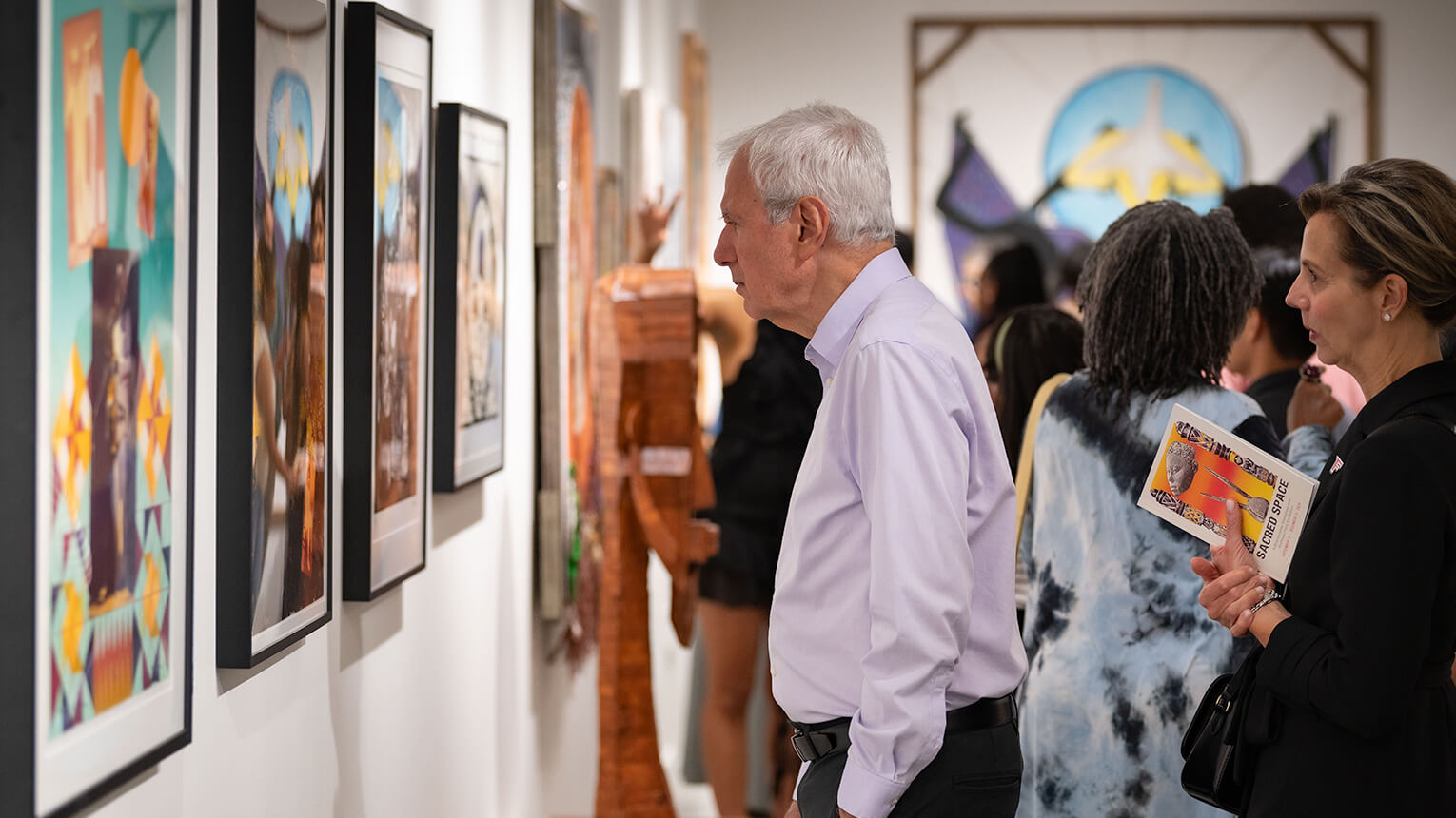 Visitors engaged in viewing art pieces in a spacious art gallery setting.