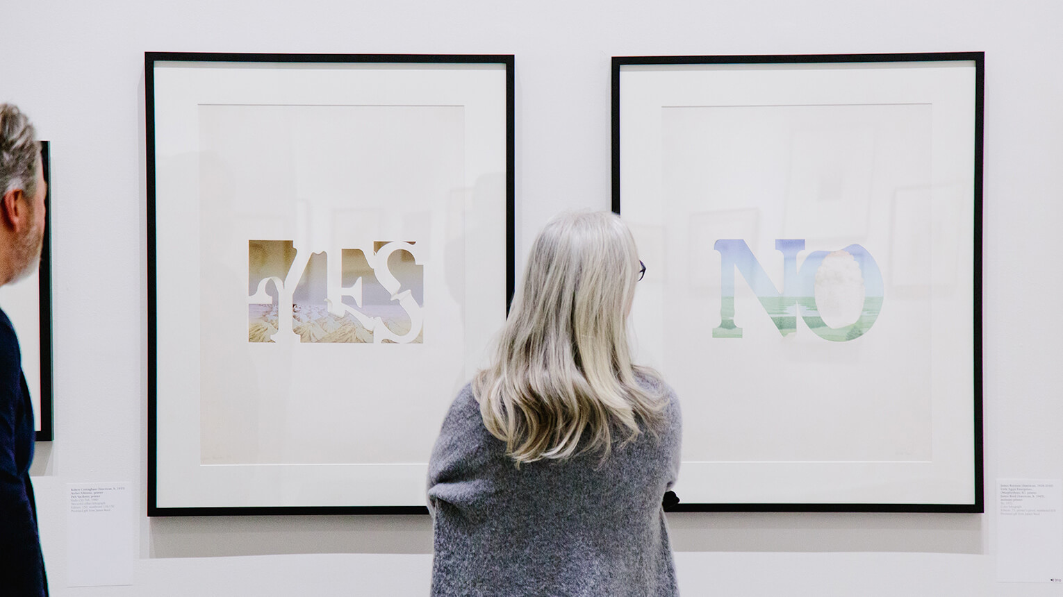 A woman observing artwork in the Walsh art gallery, engaged in the artistic experience around her.