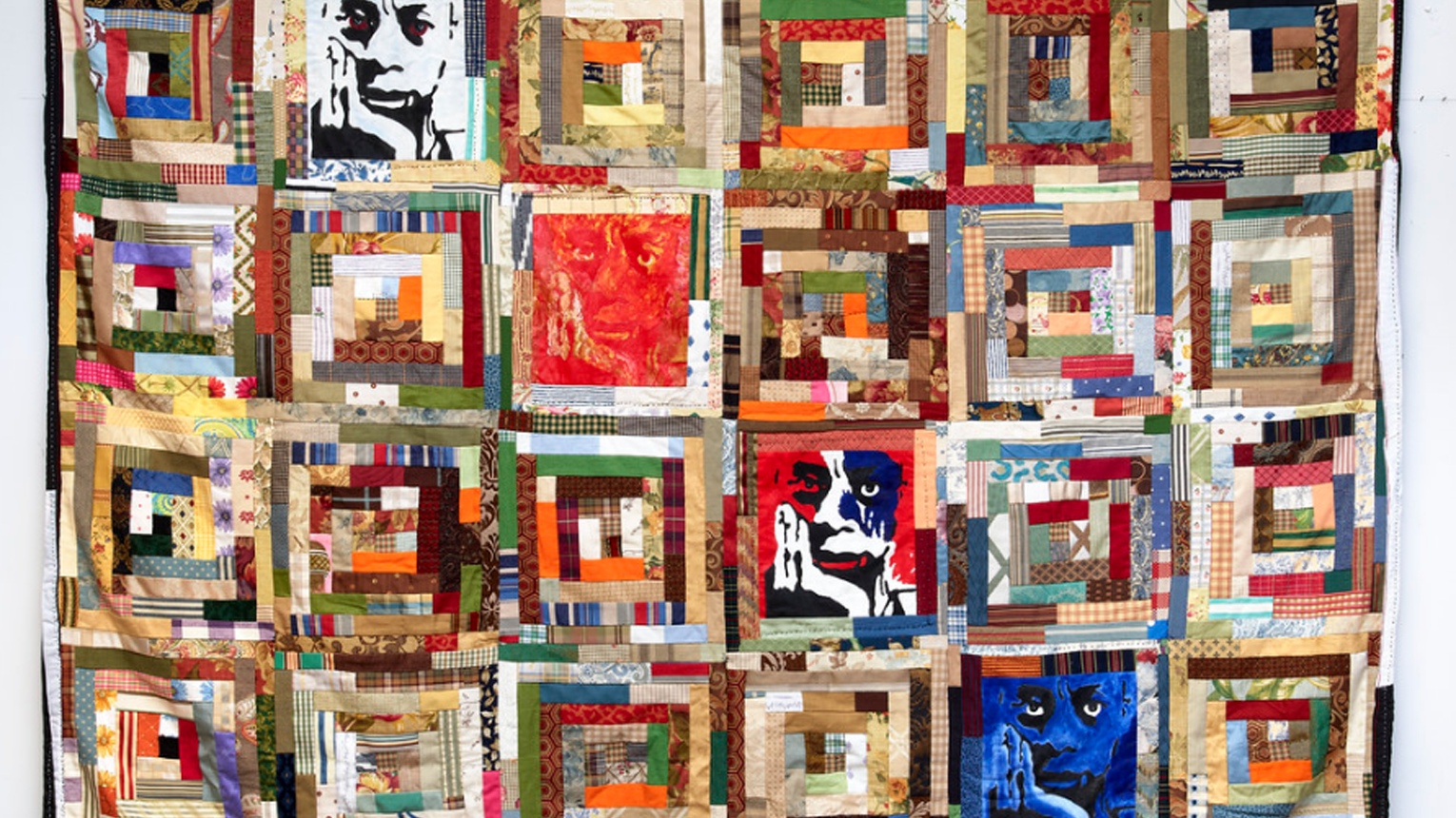 Quilt with several multi-colored squarish segments. Colored rectangles spiral inward within each square segment. Four stylized portraits of a man occupy four of the squarish segments.