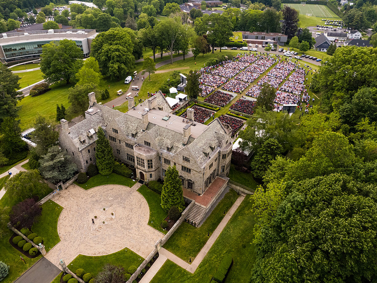 Aerial perspective of Bellarmine Hall enveloped by dense trees, highlighting its impressive architecture and serene setting.