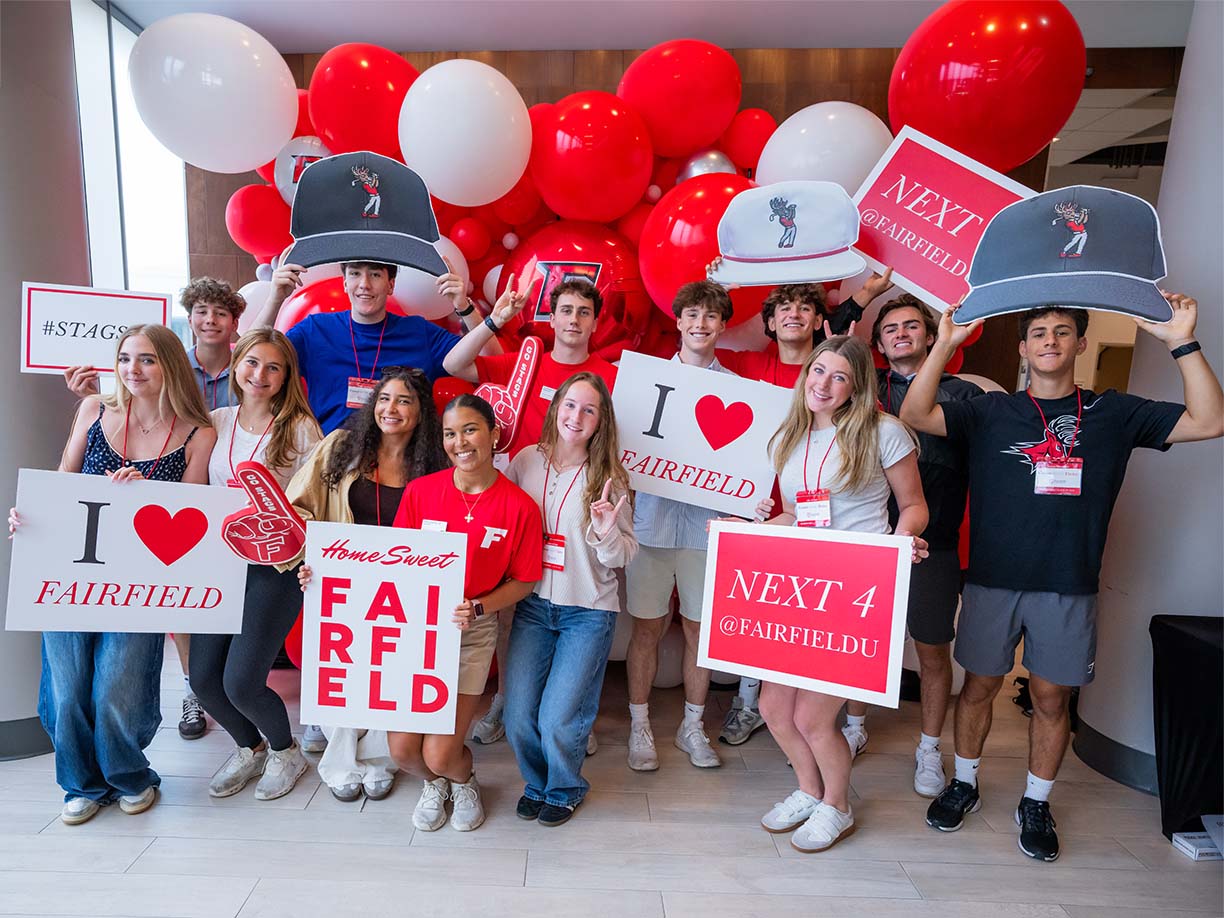 A diverse group of people holding colorful signs that read "I Love Fairfield" in a public gathering.