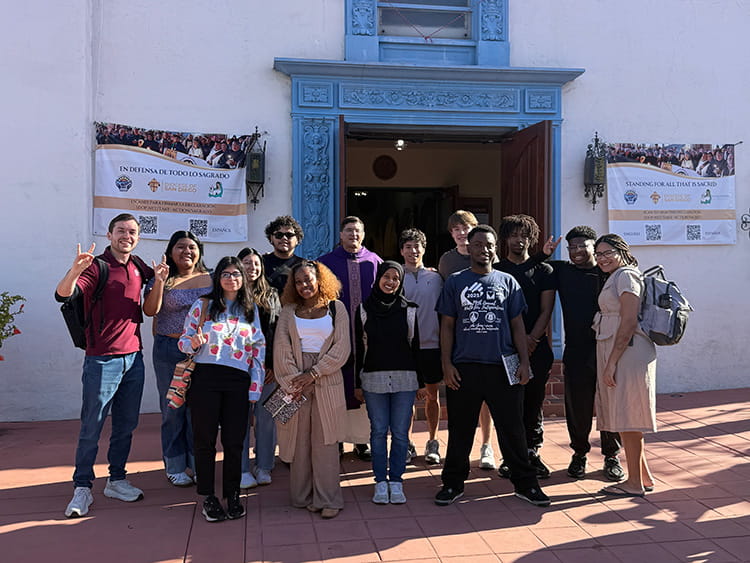 Campus Ministry students taking a group photo in front of a decorative doorway in the Barrio Logan neighborhood.