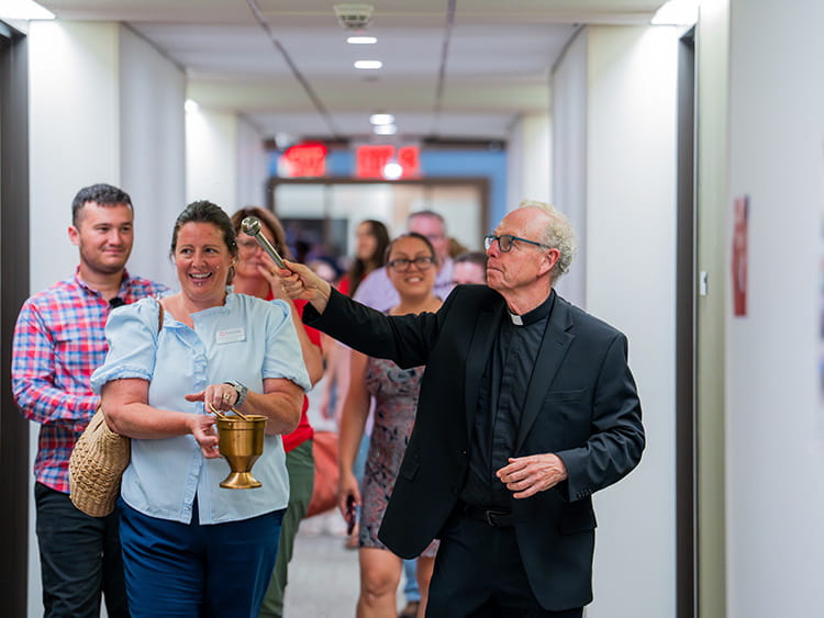 Rev. John Savard, S.J. blessing each individual room with holy water in Corrigan Hall, Fairfield's newest residence hall.