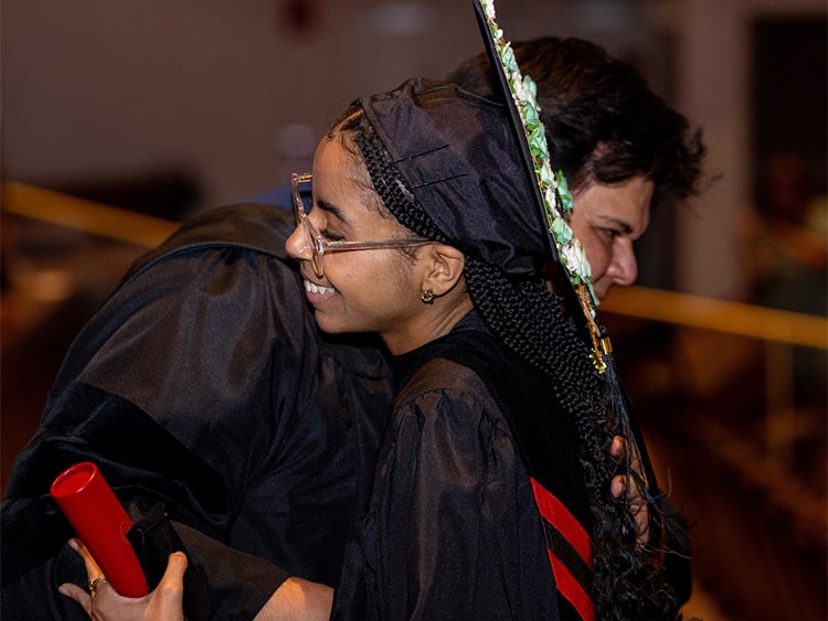 Fairfield Bellarmine graduate hugging her friend following the Commencement ceremony as they celebrate their graduation and accomplishments.