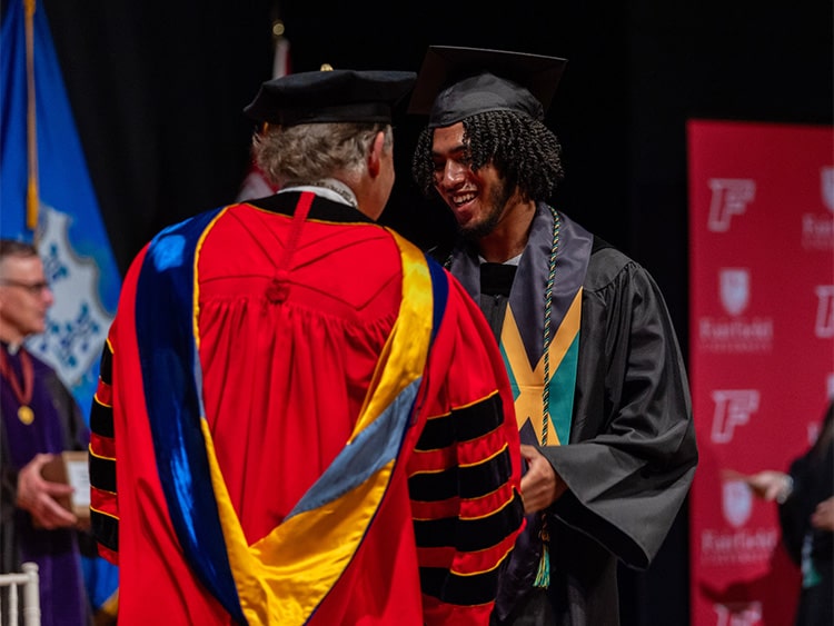 Fairfield University President conferring and bestowing an associate's in science degree to a graduate from Fairfield Egan.