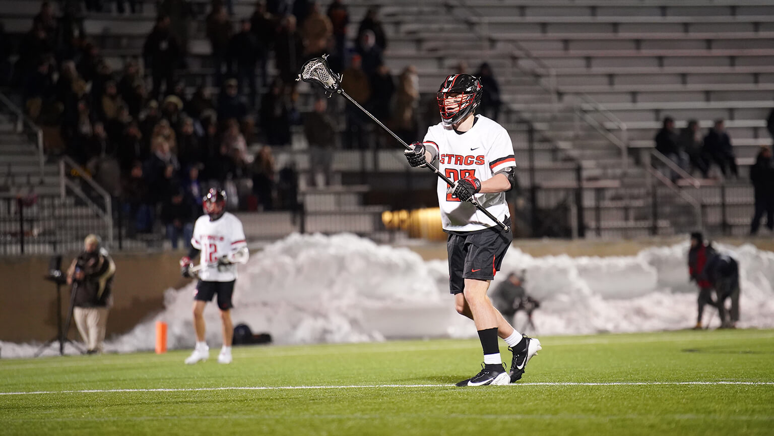 A Fairfield University lacrosse player in action on the field, skillfully holding a stick ready for play.