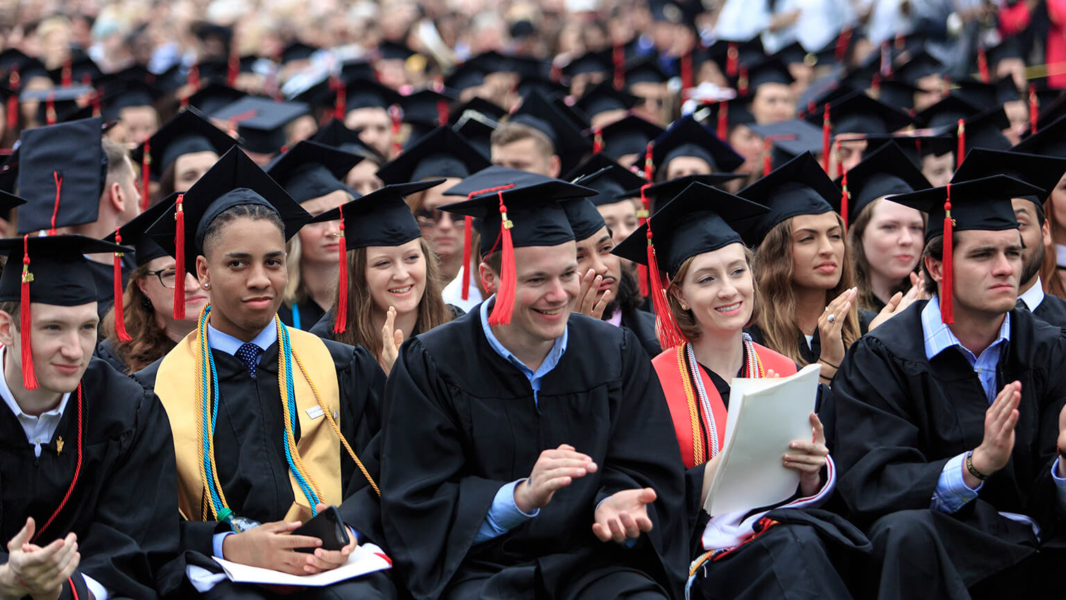A row of graduates in caps and gowns, seated and ready for their graduation ceremony. 