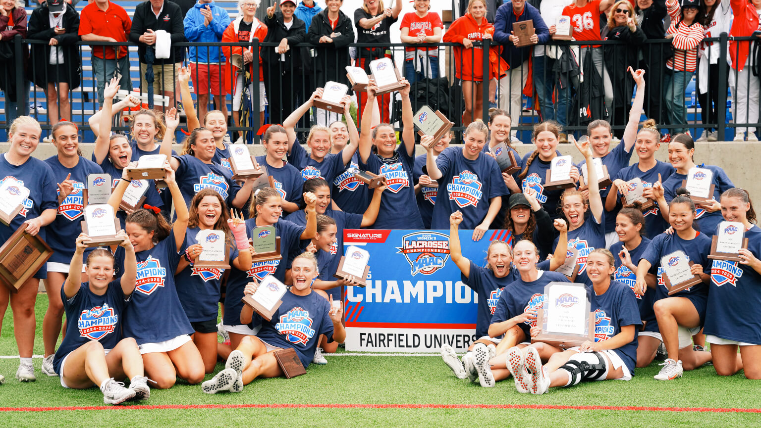 Fairfield University women's lacrosse team proudly poses together with their championship banner, celebrating their victory.  