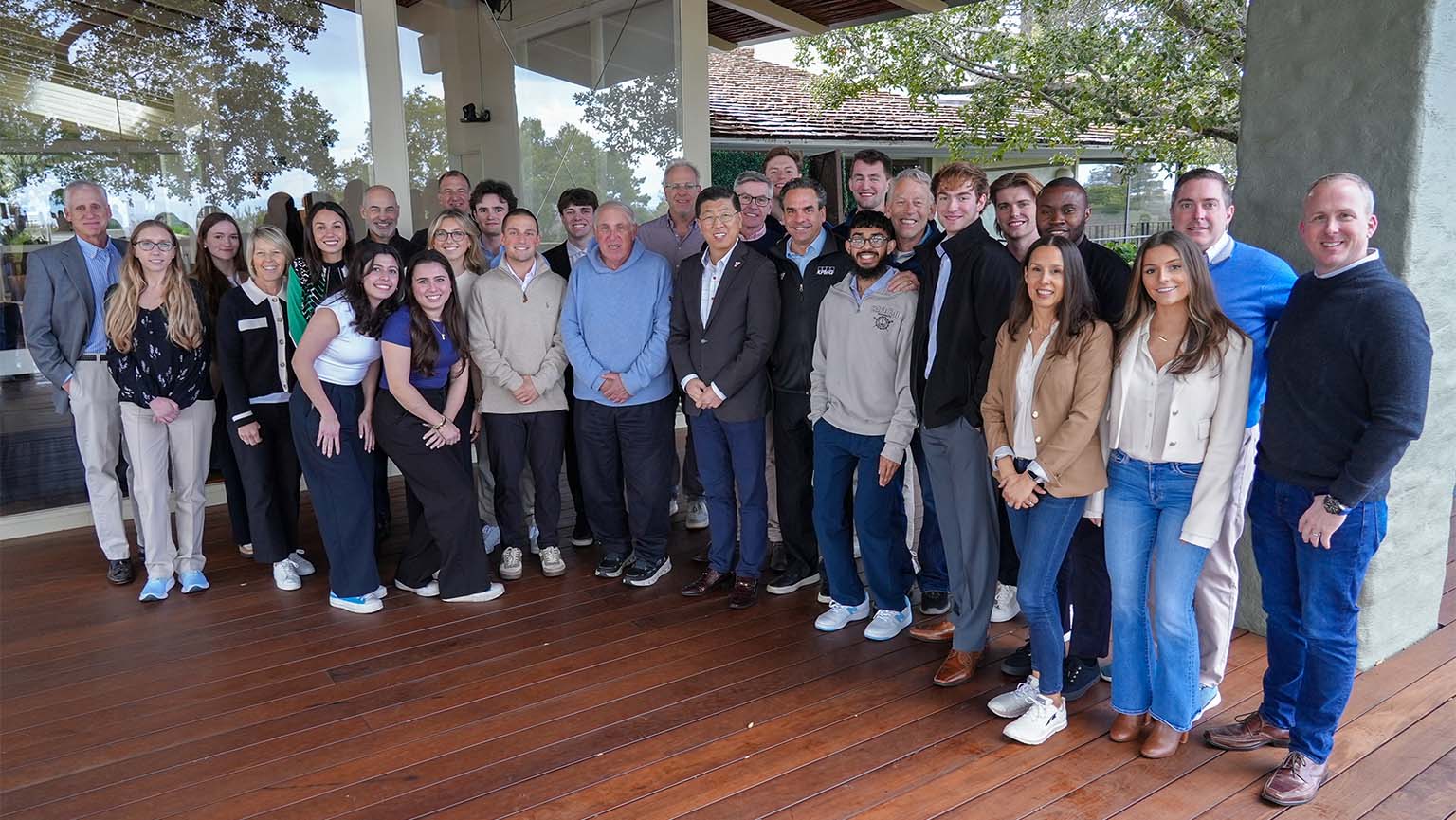 Image of a group of Dolan students, faculty, and alumni standing together on a wooden deck