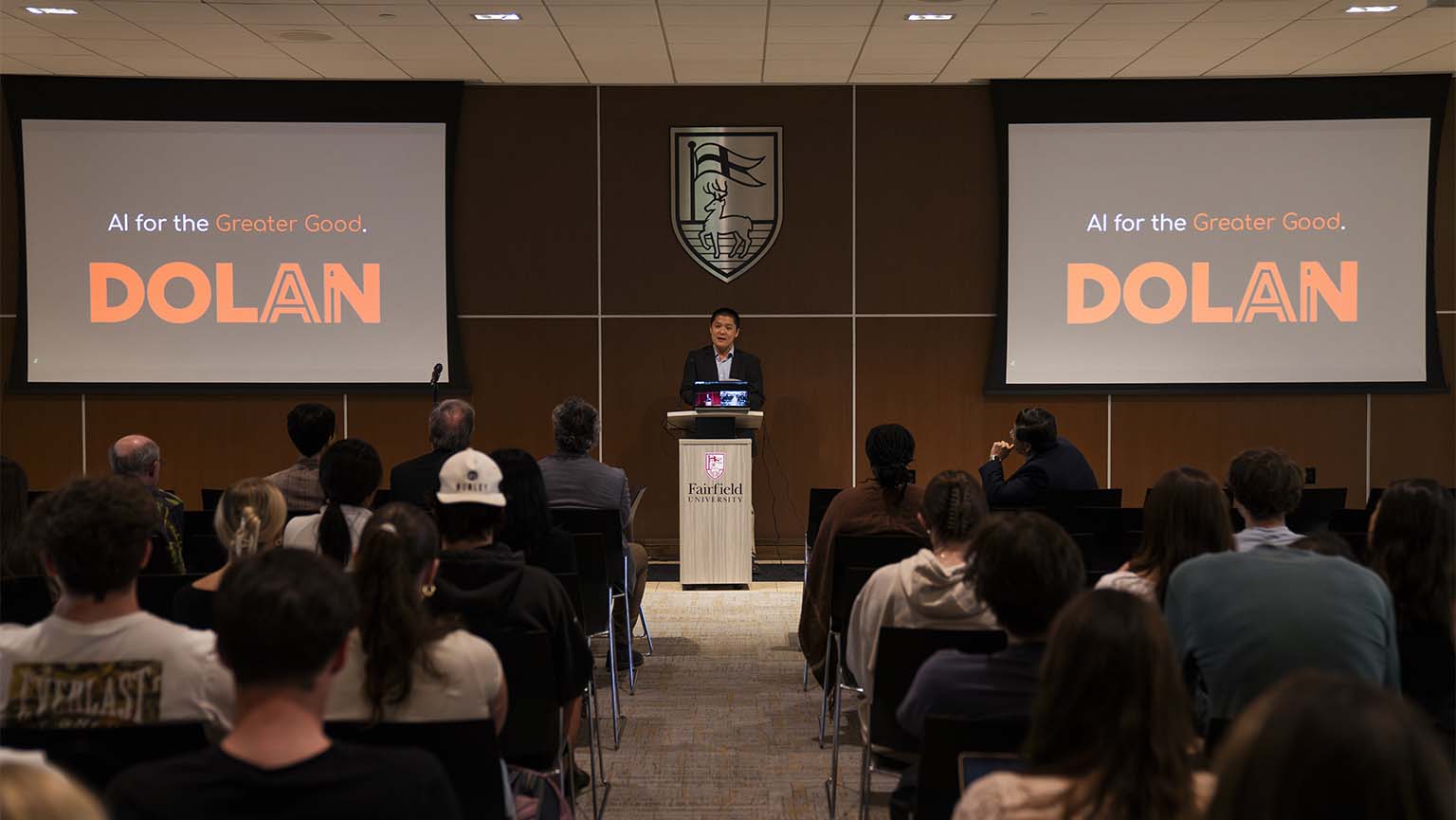 Image of a man standing at a podium, addressing a crowd during a presentation