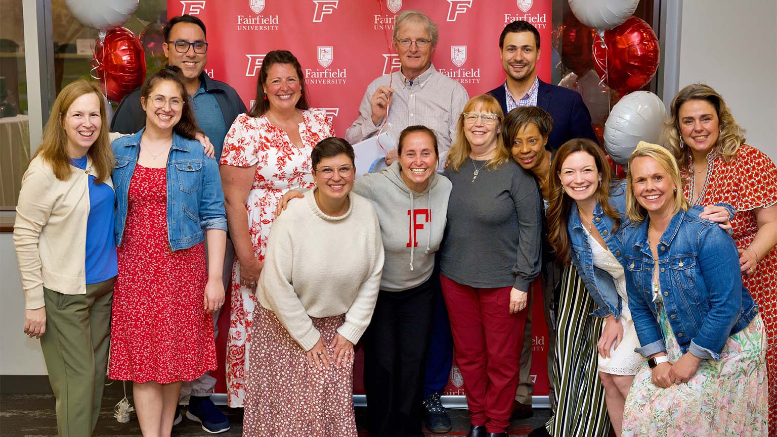 Image of a group of smiling people poses together in front of a colorful banner.