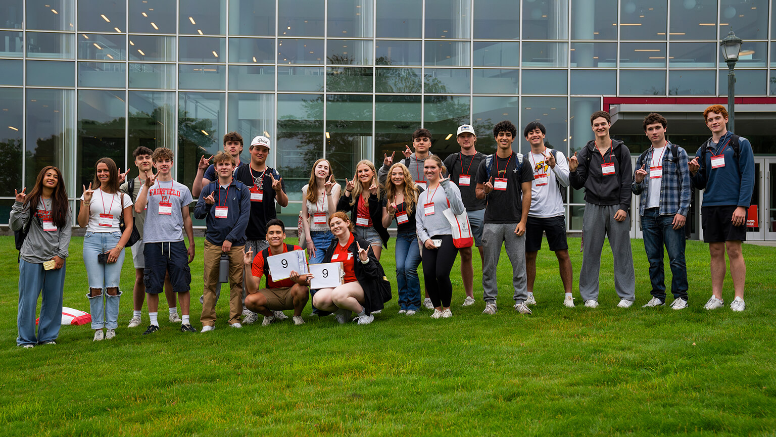 A group of students smiling and posing for a photo in front of the Charles F. Dolan School of Business building on campus.