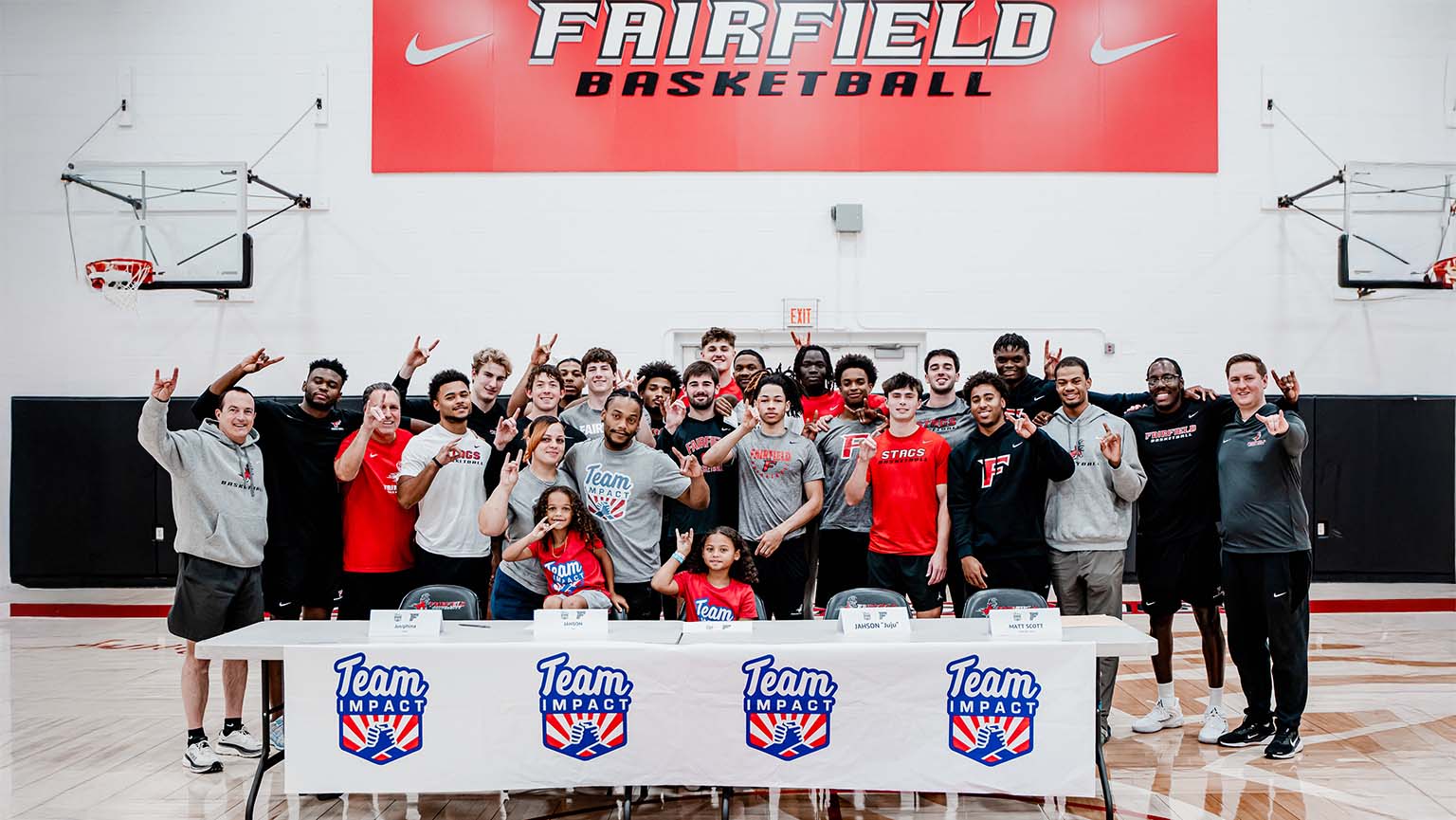 The team gathers for a cheerful photo in front of a large banner, highlighting their spirit and teamwork.