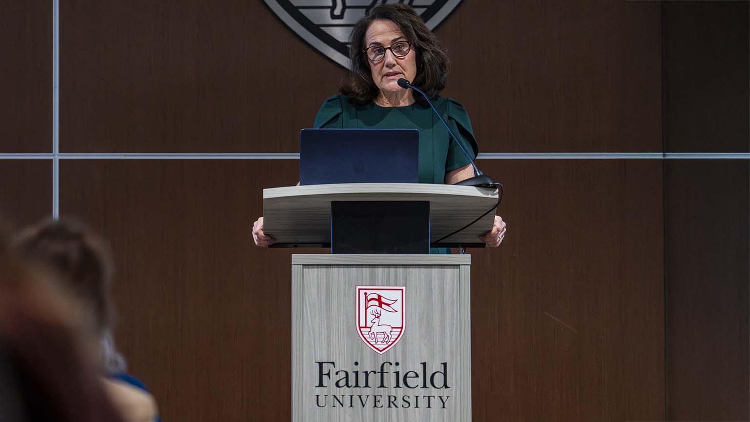 Eileen O’Shea, DNP speaks confidently at a podium, addressing a crowd with enthusiasm.