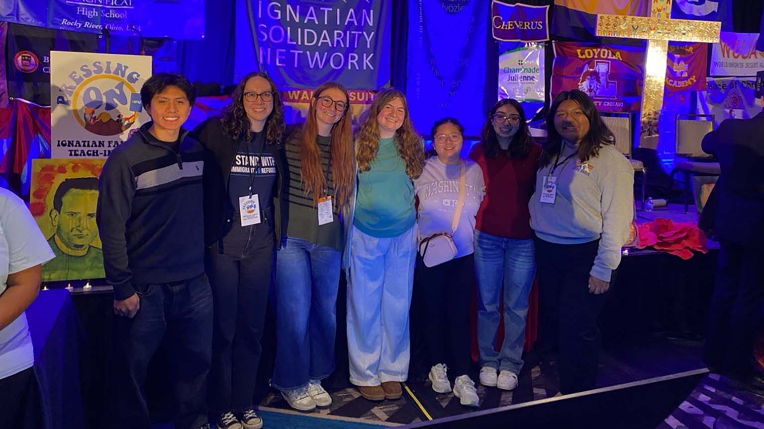 Several individuals pose together in front of a large banner, showcasing a sense of community.