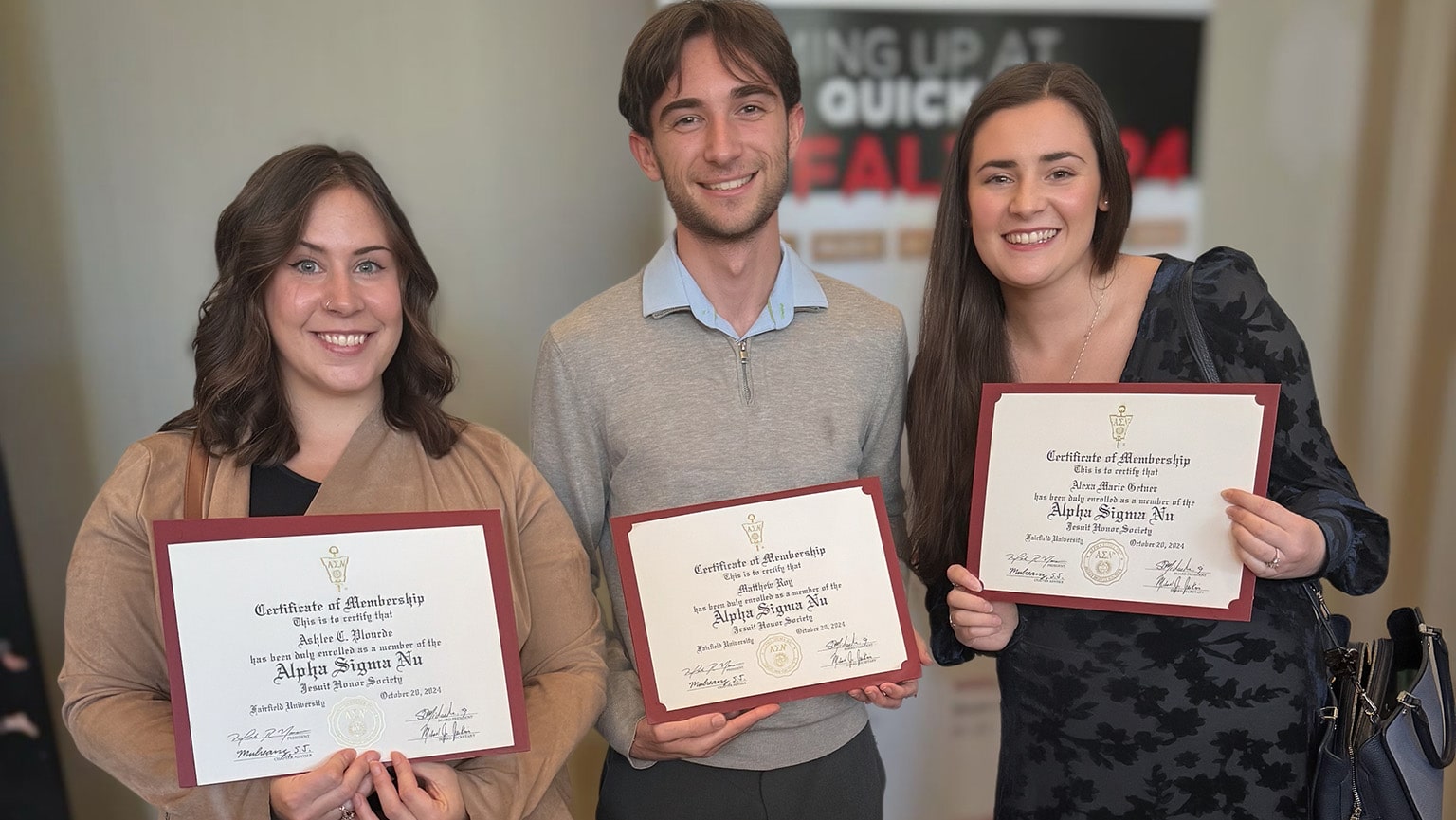 Three students proudly displaying their Alpha Sigma Nu (ASN, National Jesuit Honor Society) membership certificates.