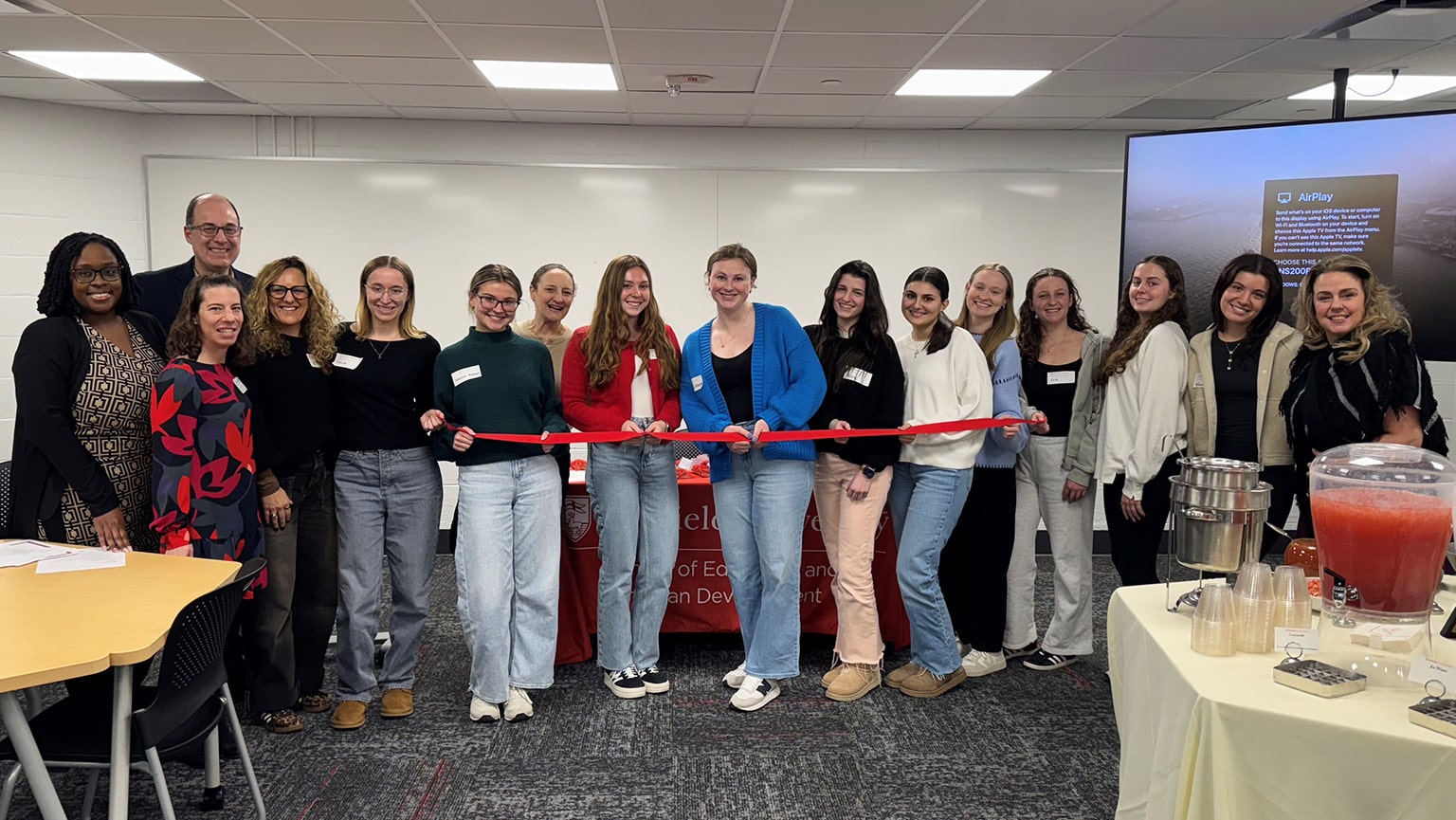 Students and program faculty posing to cut a ribbon for the launch of the Curriculum and Instruction program.
