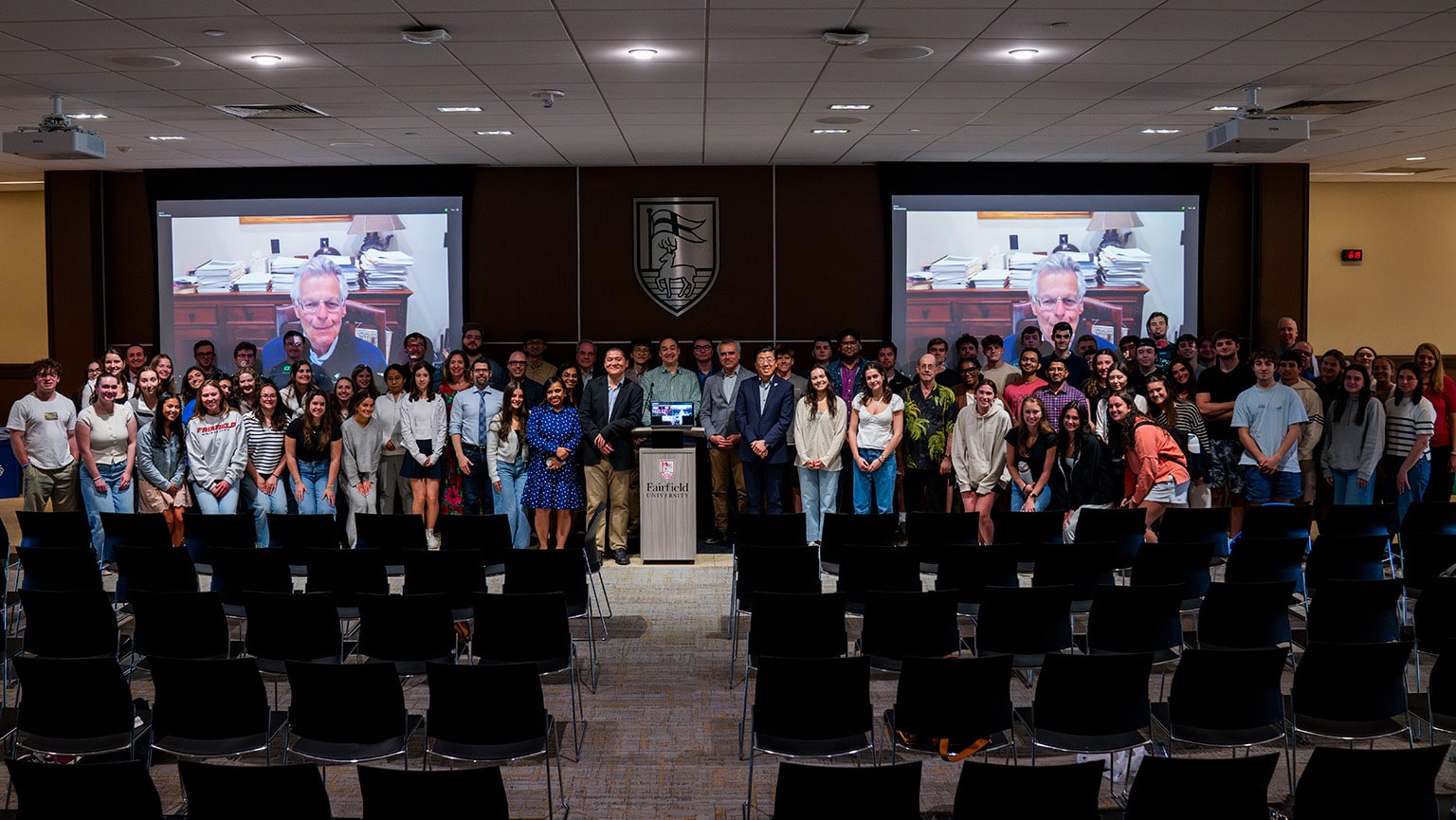 Business students, faculty, and staff posing for a group photo with a Zoom speaker after the launch of the new AI and Tech institute.