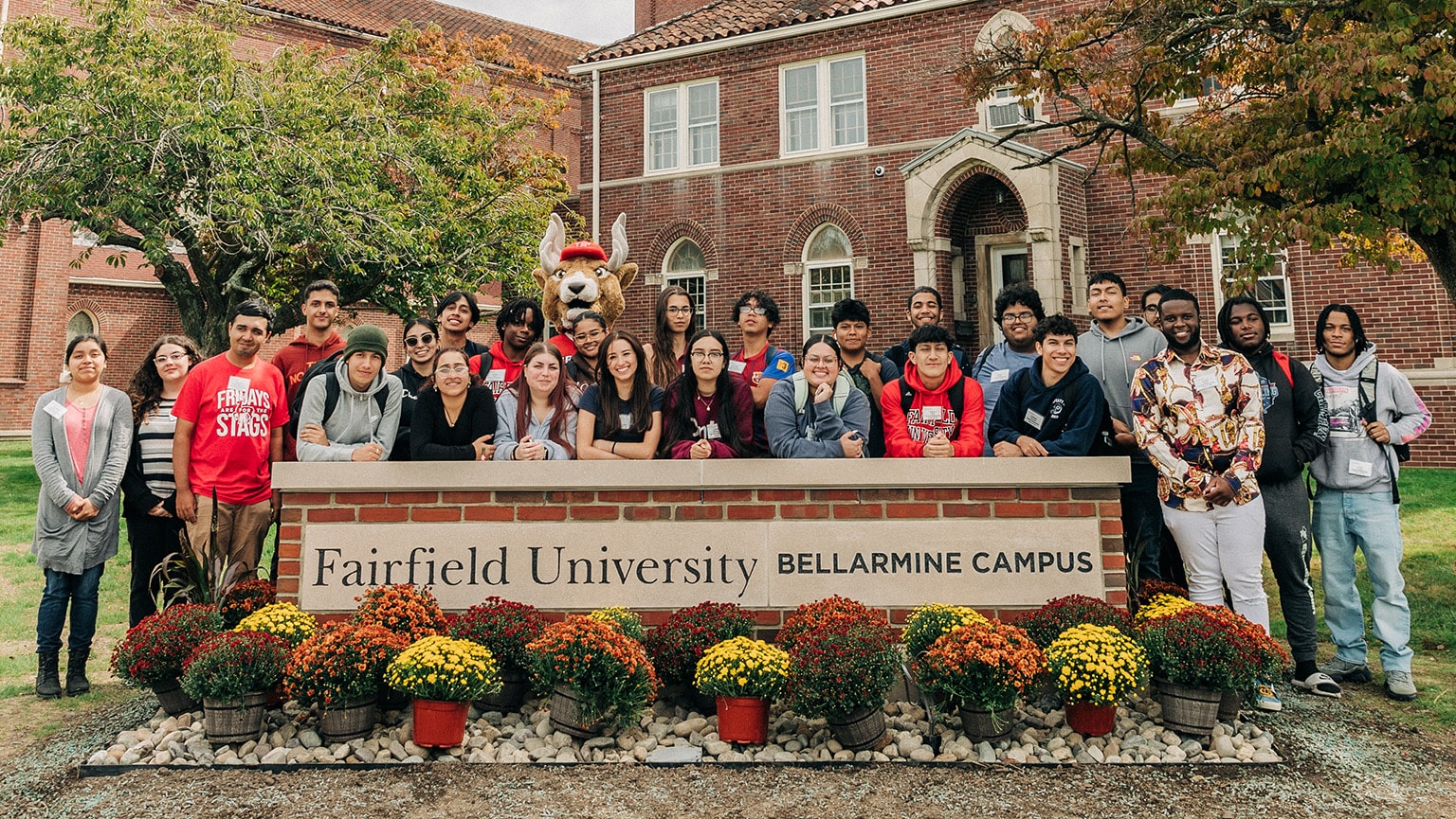 Members of the first graduating class of Fairfield Bellarmine standing proudly behind the brick campus sign.