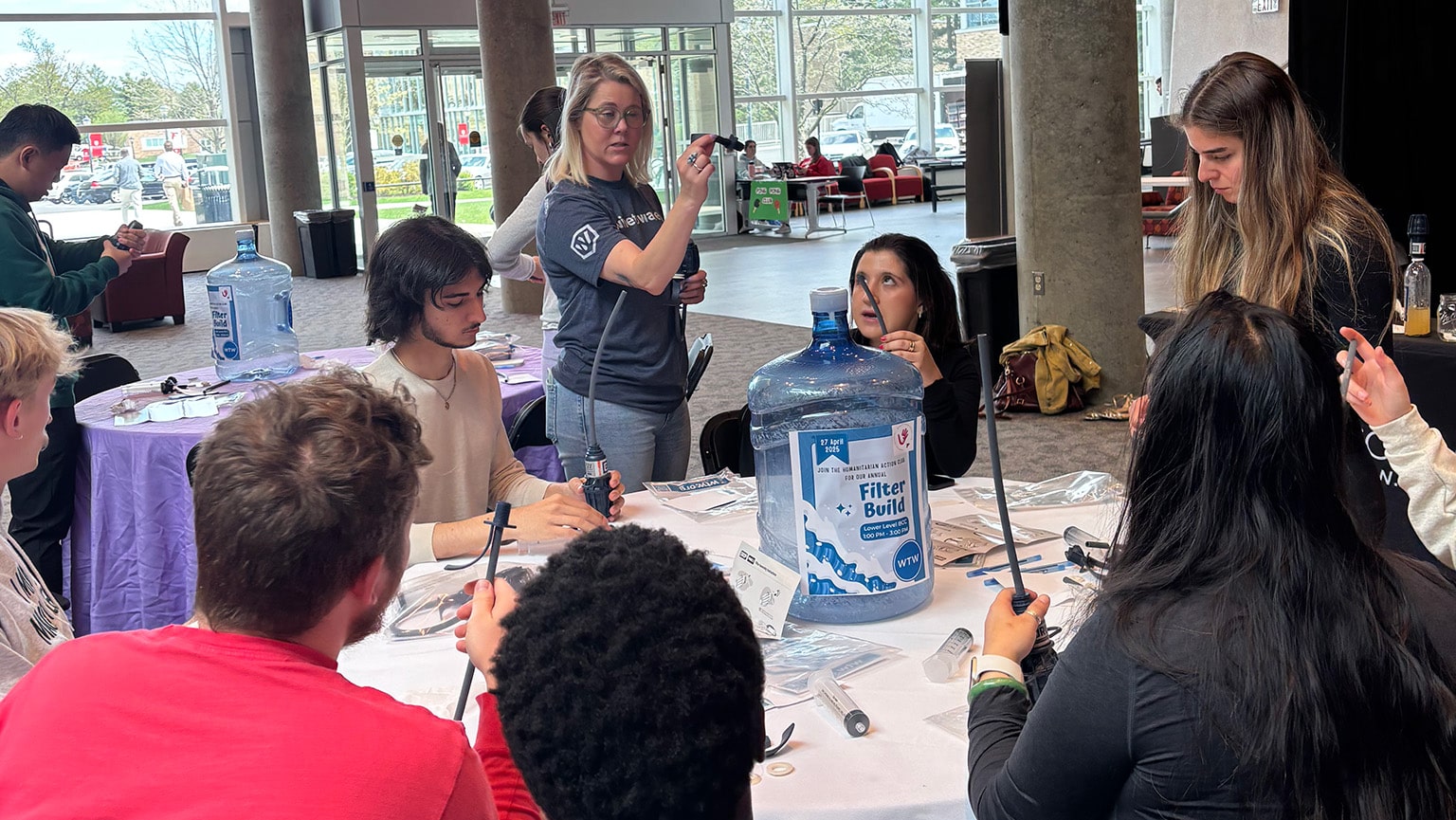 Student members of the Humanitarian Action Club working at a table to assemble water filters.