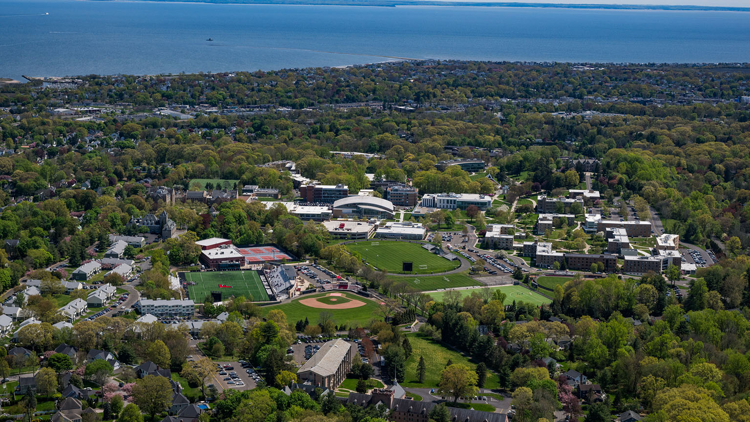 Aerial view of the entirety of Fairfield's sprawling, green campus with the Long Island Sound in the background.