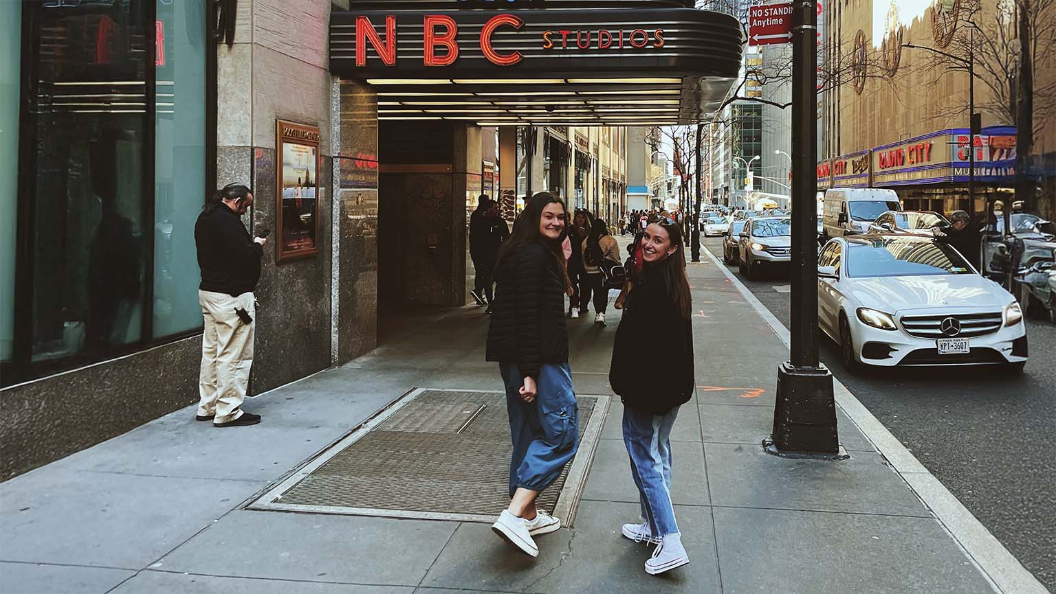 Image of two women posing together in front of an NBC building, smiling and enjoying their time in the city.