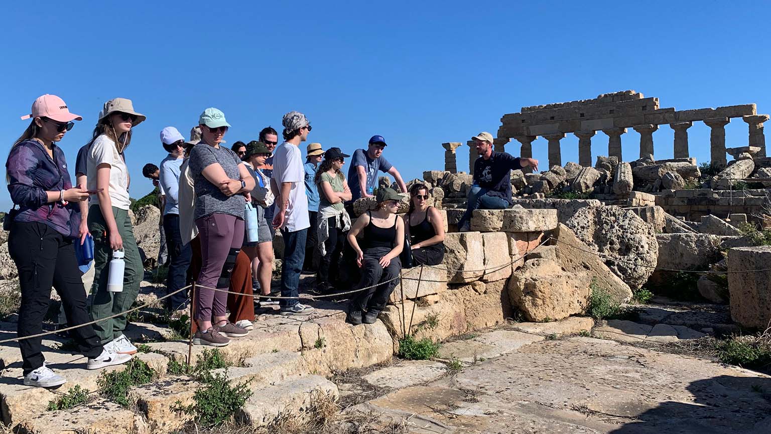 Image of a group of people gathered on the steps of an ancient building, enjoying the historic architecture around them.