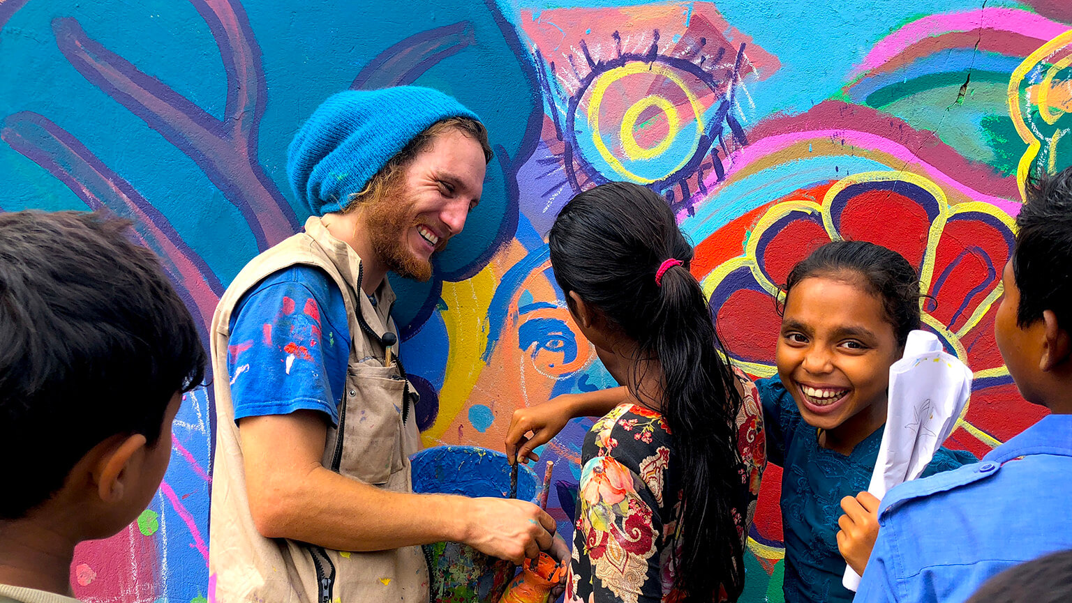 Max Frieder, EdD painting a wall mural with local refugees.