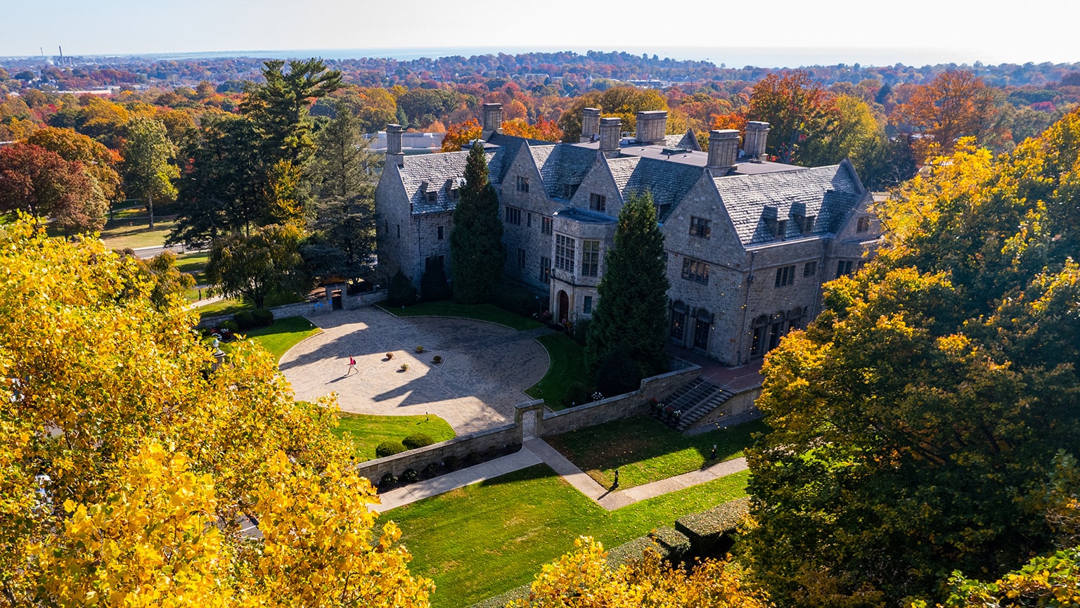 A substantial structure, Bellarmine Hall at Fairfield University campus is enveloped by trees, blending architecture with nature in a tranquil setting. 
