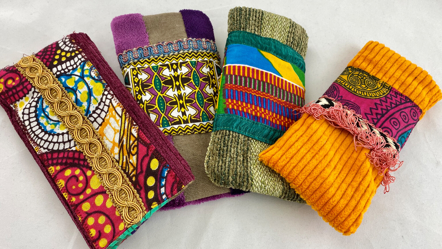 A collection of four colorful purses, each showcasing distinct and vibrant patterns, displayed side by side.