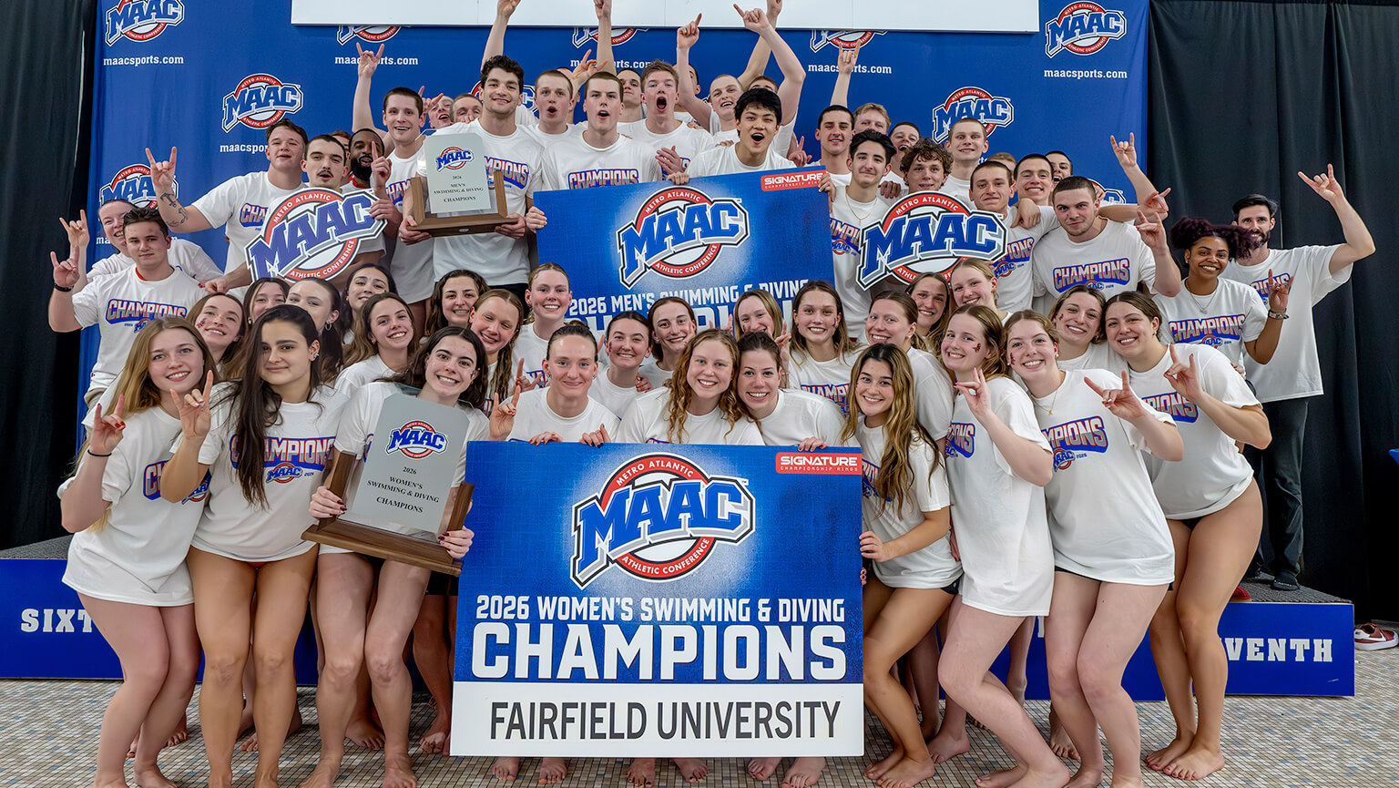 A jubilant Fairfield swimming and diving team celebrates victory. Men and women in white shirts hold trophies and a "2026 Champions" banner. Joyful, triumphant atmosphere.