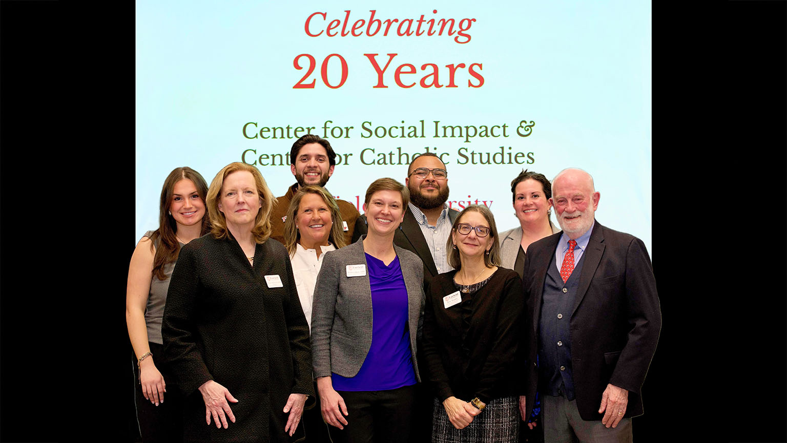 A group of people celebrating 20 years of social impact and care studies, smiling and standing together.