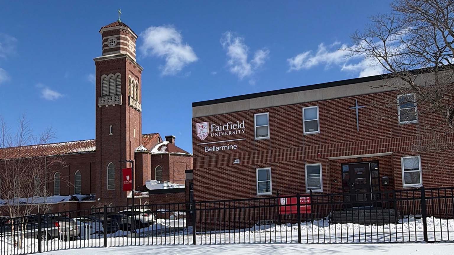 Image of a red brick building with a prominent clock tower rising in the background.