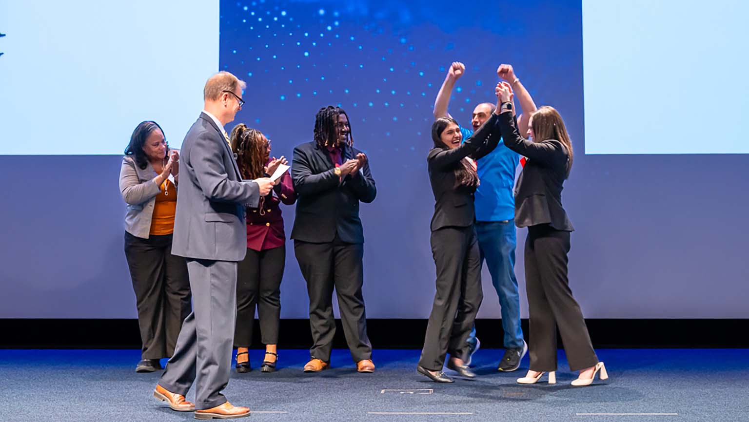 A group of people on stage, with one person raising a fist in a gesture of solidarity or empowerment.