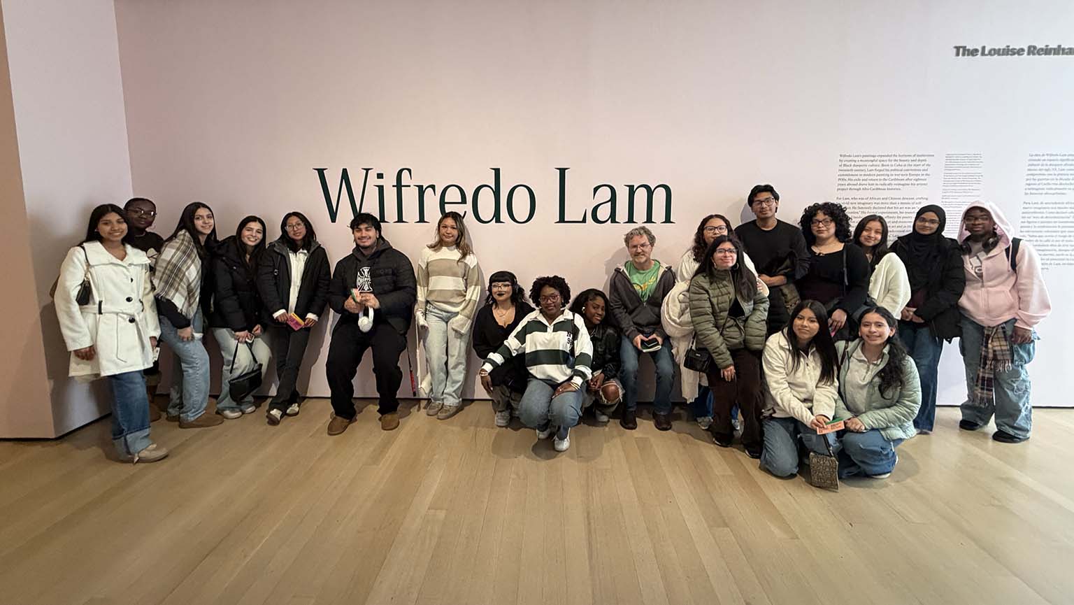 A group of smiling people posing together in front of a colorful wall.