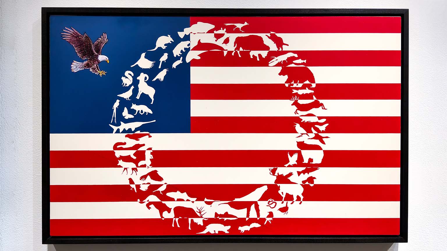 American flag artwork by James Prosek, titled “Invisible Boundaries”, featuring silhouettes of various animals forming a circular shape in the center, with a bald eagle in the blue square.