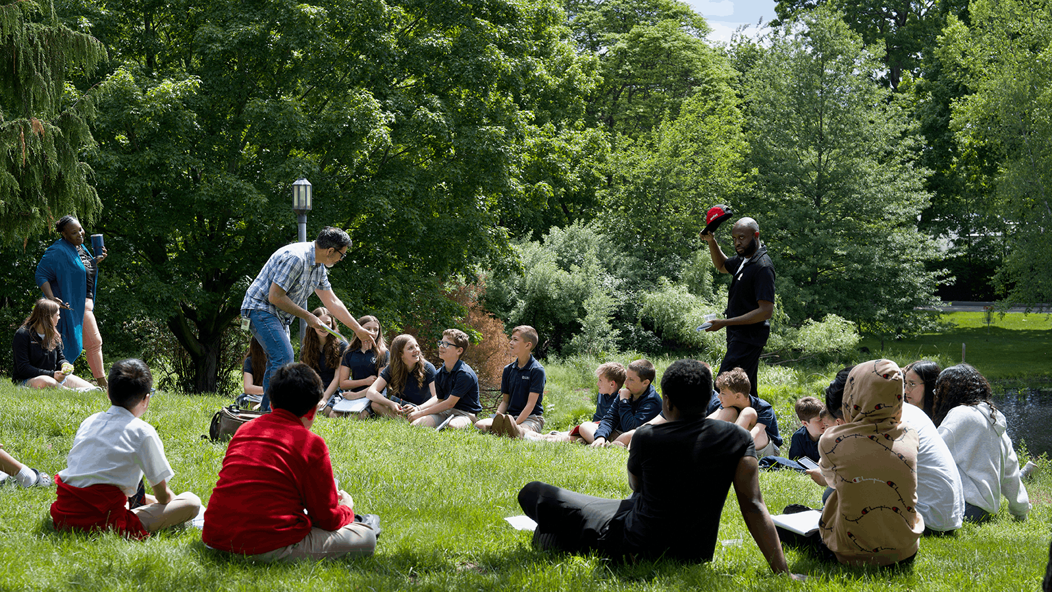 Writing workshop students participating in a group activity while sitting outside on a bright, sunny day.
