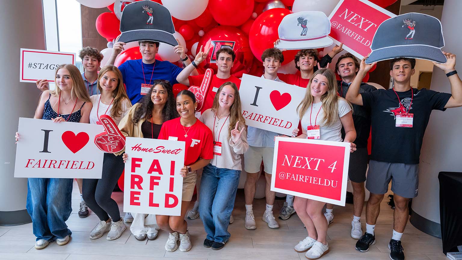 A group of people joyfully holding signs that say "I Love Fairfield" in a vibrant outdoor setting.