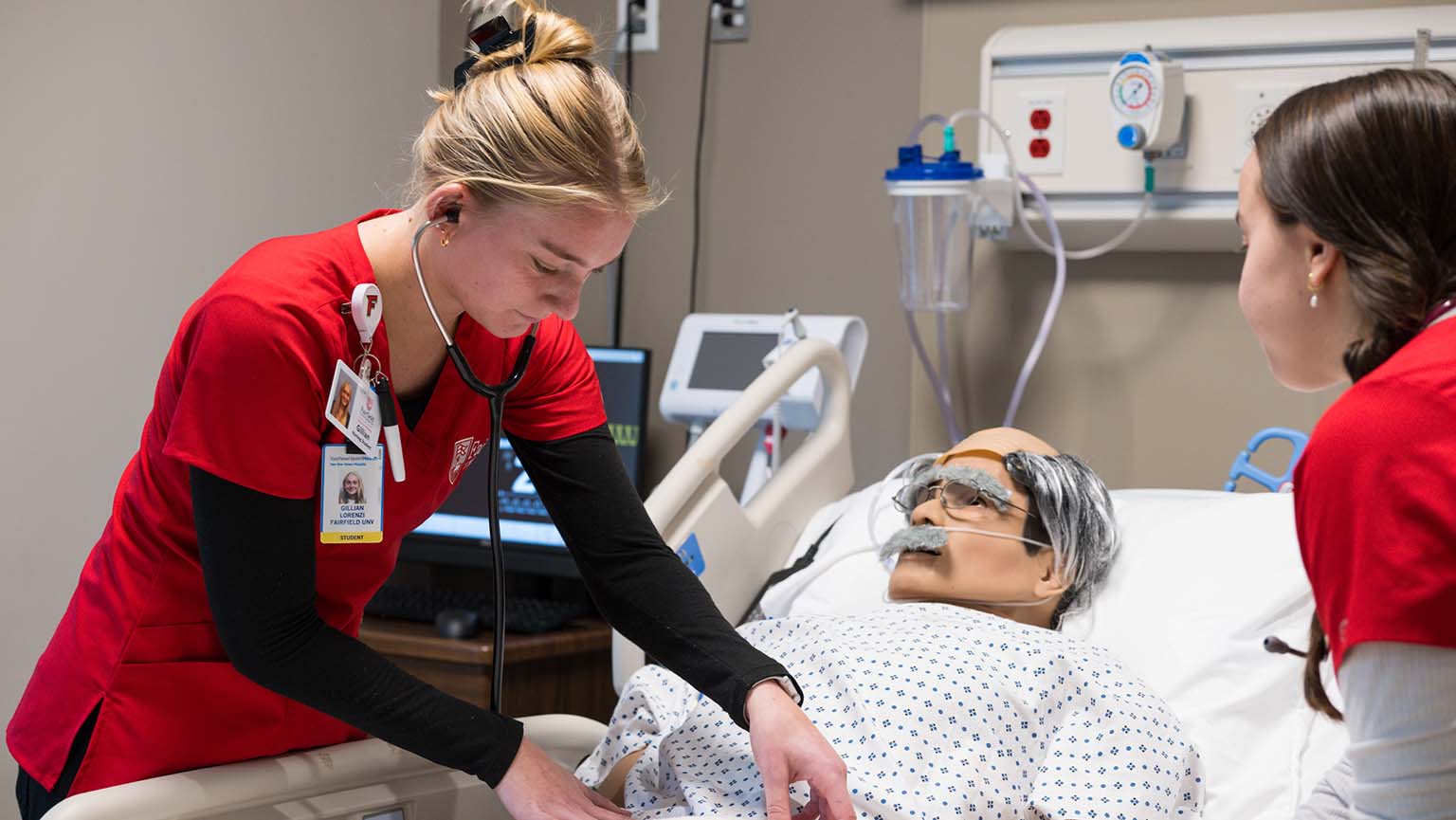 A nurse leans over a patient in a hospital bed, offering assistance and medical care.